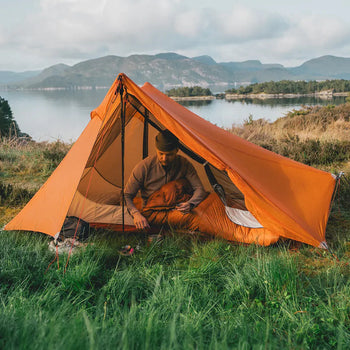 Person laver kaffe i telt ude i naturen 