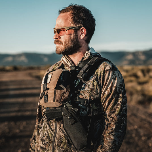 Mand med Wiley X solbriller og camouflagejakke under udendørs aktivitet.